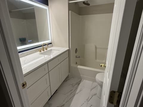 Full bathroom remodel with marble-look tile surrounding the tub