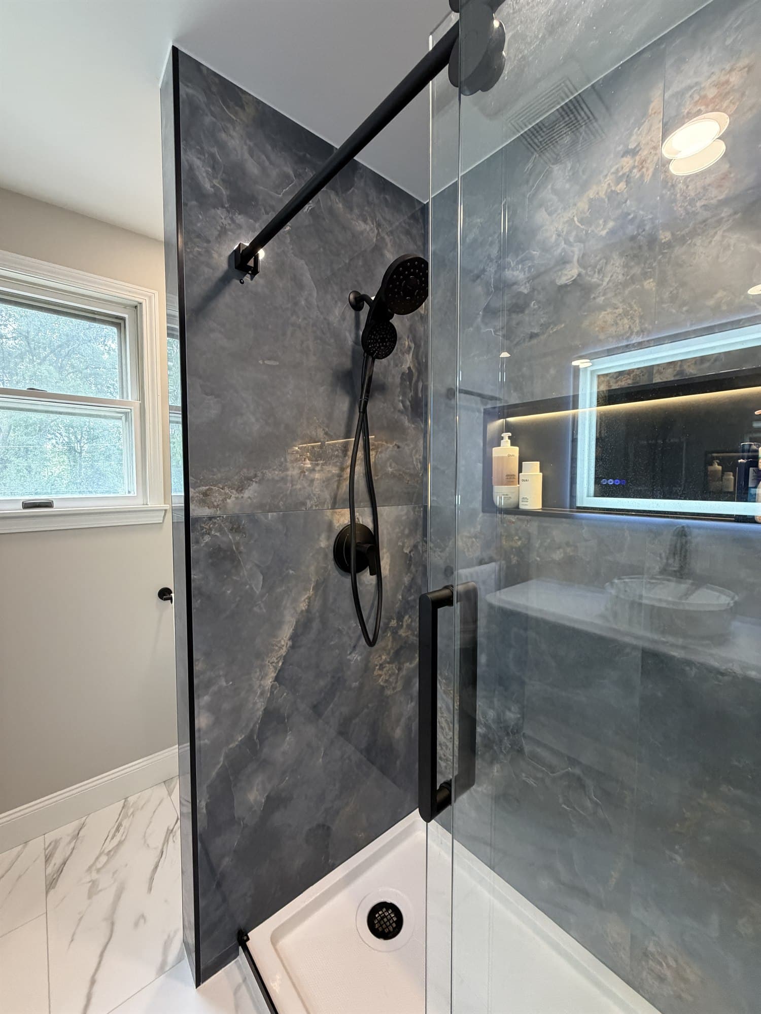 Matte black shower fixtures against slate-look tile, with daylight from the bathroom window